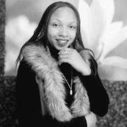 A black and white headshot of an artist wearing a fur vest